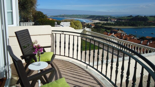 Ein Balkon mit Blick auf eine Küstenlandschaft, einschließlich eines Gewässers und ferner Hügel.