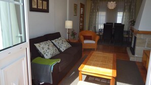 Ein Wohnzimmer mit einer Couch, einem Sessel, einem Tisch und einem Essbereich mit Stühlen und einem Tisch.