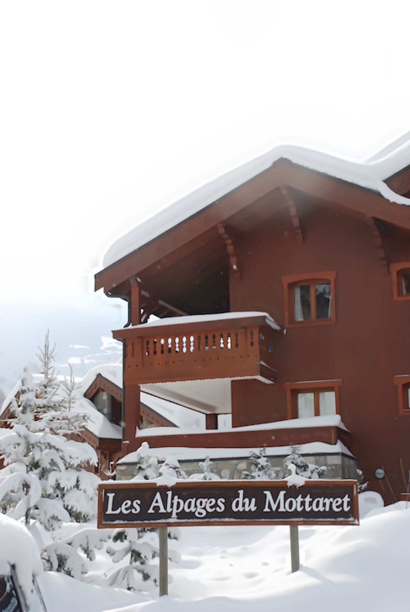 Un bâtiment enneigé sur lequel on peut lire l’inscription « Les Alpes du Mottaret ».