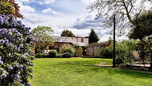 A well-maintained garden with a lawn, a wooden fence, and a house with a sloped roof.