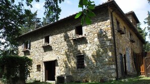 A stone building with a large open doorway, multiple windows, and a sloped roof. - Ancient stone house in the heart of the Chianti Classico (Panzano in Chianti)