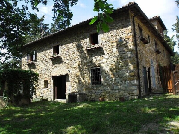 A stone building with a large open doorway, multiple windows, and a sloped roof.