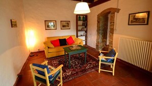 A cozy living room with a sofa, two chairs, a coffee table, and a bookshelf. - Ancient stone house in the heart of the Chianti Classico (Panzano in Chianti)