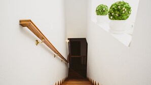 Eine Holztreppe mit Handlauf, die zu einer dunklen Tür führt.
