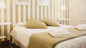 Ein Hotelzimmer mit einem Doppelbett, zwei Nachttischen mit Lampen, einem Kleiderschrank und gestreifter Tapete.