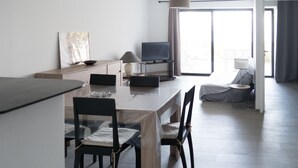 A modern, well-lit living room with a dining area, a flat-screen TV, and a large window providing natural light. - Coti Chiavari: House / Villa - Coti-chiavari (Coti-Chiavari)
