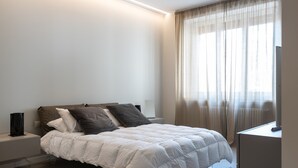 A modern bedroom with a bed, bedside tables, and a large window with curtains. - Design and Comfort in the Heart of Catania by Wonderful Italy (Catania)
