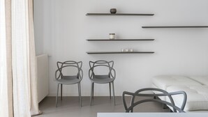 A modern room with a white sofa, two grey chairs, and three shelves with decorative items. - Design and Comfort in the Heart of Catania by Wonderful Italy (Catania)
