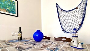 Ein Esstisch mit einer Tischdecke mit Seestern-Motiv, einer blauen Vase, einer Weinflasche und einem dekorativen Netz.