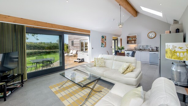 Een moderne woonkamer met een glazen salontafel, een bank en uitzicht op de tuin.