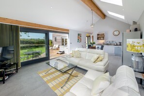 Un salon moderne avec une table basse en verre, un canapé et une vue sur le jardin.