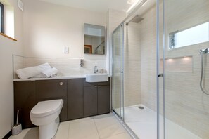A modern bathroom with a glass-enclosed shower, a white toilet, and a dark-toned vanity. - Private lodge with countryside views and Hot tub (Ilminster)