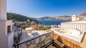 Eine Dachterrasse mit Whirlpool, Essbereich und herrlichem Blick auf das Meer und die Hügel.