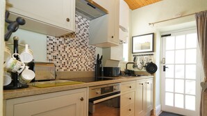 Une cuisine avec un mur recouvert de carreaux, une cuisinière, un four et une porte dotée d’une fenêtre.