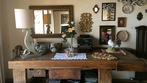 Una mesa de madera con varios objetos, entre ellos una máquina de escribir, un jarrón con flores y platos decorativos.