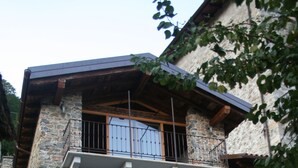Un edificio de piedra con un balcón, una puerta de madera y una ventana con flores.