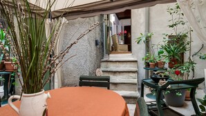 A rustic outdoor seating area with a table and chairs, surrounded by potted plants and a stone wall. - NAVONA ROMANTIC LOFT (Roma)