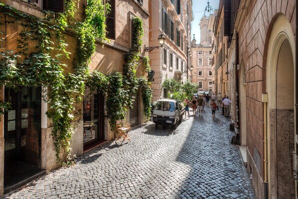 Une rue pavée bordée de bâtiments historiques, un fourgon garé et des gens qui se promènent.