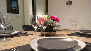 A dining table set with plates, cutlery, and glasses, with a flower vase on the center. - NAVONA ROMANTIC LOFT (Roma)