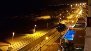 Ein nächtlicher Blick auf einen gut beleuchteten Stadtbereich mit Pool, Straßenlaternen und einem gemusterten Pflasterweg.