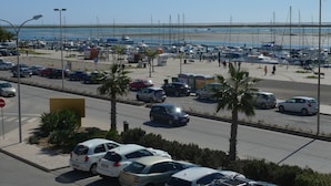 Un estacionamiento con coches y un puerto deportivo al fondo.