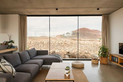 Minimalistinen talo, jossa on lämmitetty uima-allas ja upea tulivuori