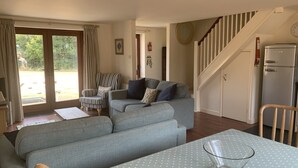 A living room with a grey sofa, a striped armchair, and a dining table with a polka dot tablecloth. - Cosy family cottage with dog-friendly garden, near Rock, Polzeath & Padstow (Wadebridge)