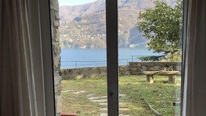 Une pièce dotée d’une porte-fenêtre coulissante donnant sur un balcon avec vue sur un lac et des montagnes.