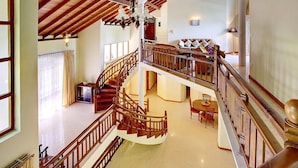Ein geräumiger Innenbereich mit einer Holztreppe, die zwei Etagen verbindet, einem Essbereich und einem Wohnzimmer mit Sofa und Dekoration.