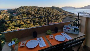A balcony with a table set for two, overlooking a forested hillside and a body of water. - Lerici, Portovenere, 5 terre... all the wonders just a few minutes from the house! (Lerici)