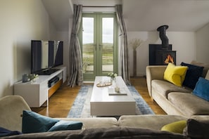 Ein Wohnzimmer mit Sofa, Couchtisch, Fernseher und Kamin.