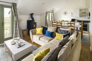 Ein Wohnzimmer mit Sofa, Couchtisch, Kamin und Küchenbereich.