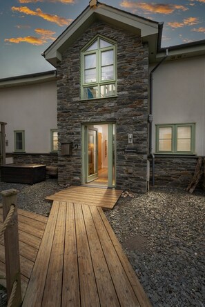 A two-story stone building with a wooden deck leading to the entrance.