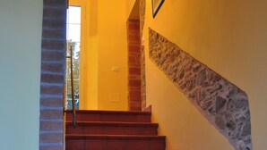 A staircase with red steps leading to a landing, flanked by a brick wall on one side and a stone wall on the other.