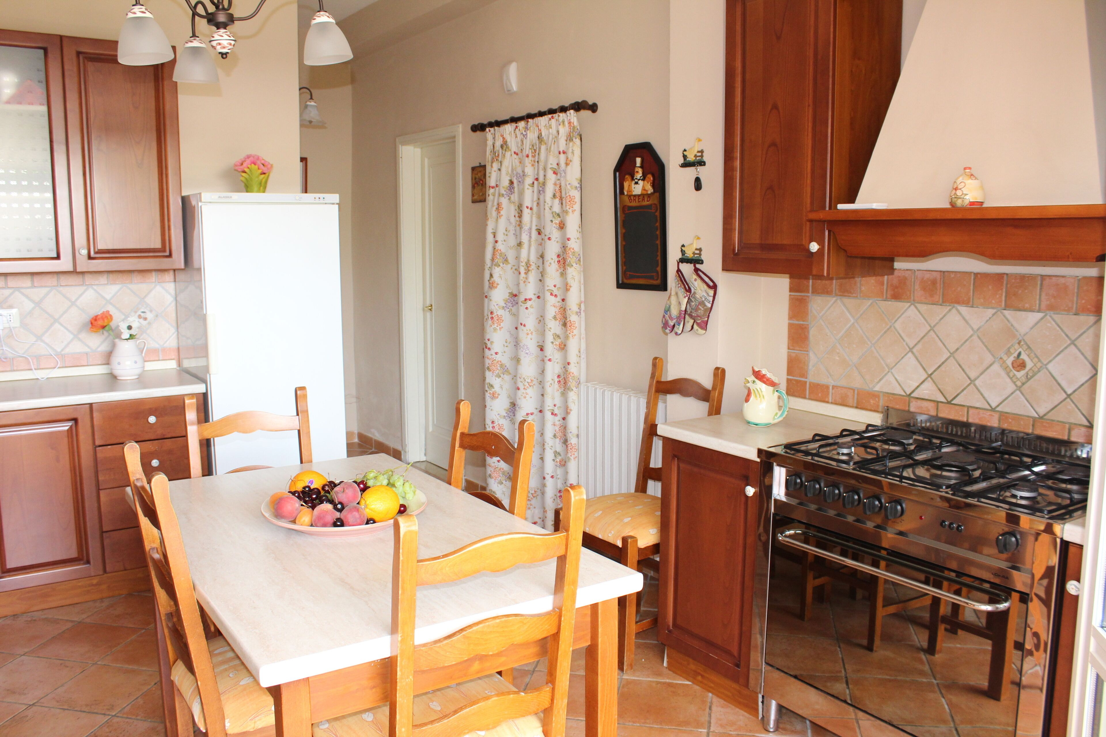 A kitchen with wooden cabinets, a white refrigerator, a stove, and a dining table with chairs.