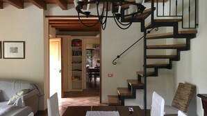 A dining area with a wooden table and chairs, a chandelier, and a staircase with a black railing. - Villa with private pool in Tuscany (Tresana)