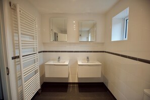 Een badkamer met twee wastafels, een handdoekrek en twee spiegels.