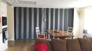 Un espace de vie comprenant un canapé marron, une table en bois et deux chaises. Il y a également un coin cuisine avec un four à micro-ondes et une cuisinière.
