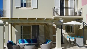 Een gebouw met twee verdiepingen met een overdekte patio, voorzien van tuinmeubels en een eethoek.