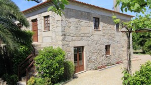 A stone building with a tiled roof, a wooden door, and a small window.