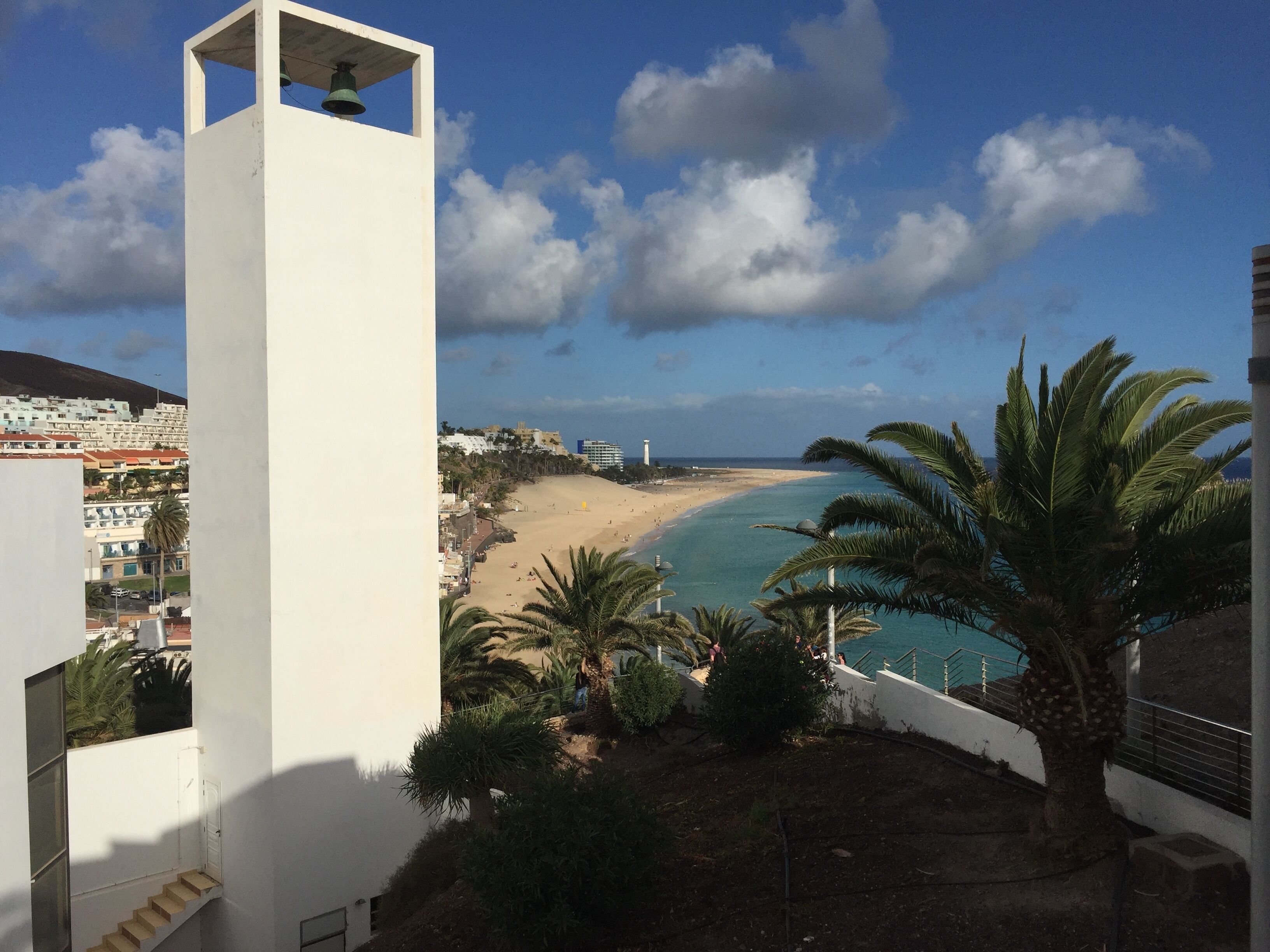 A coastal view with a beach, a lighthouse, and a white tower.