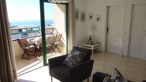 A living room with a sofa, a dining area with chairs and a table, a lamp, and framed artwork on the wall. - Buenavista, 2 bedrooms, Wifi, very sunny, terrace, sea views, central location (Morro Jable)