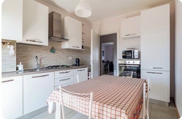 Efficient kitchen with gas stove, coffee maker, and microwave, perfect for meal preparation and dining.