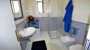 Et badeværelse med bruser, to håndvaske, toilet og et spejl.