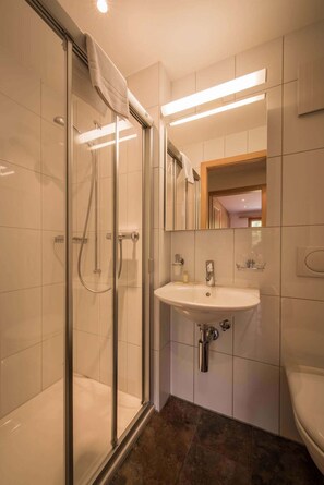 A modern bathroom with a glass shower enclosure, a white sink, and a mirror above the sink.