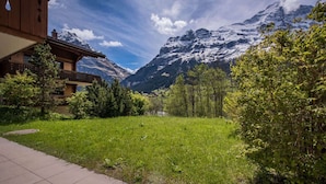 A mountain lodge with a wooden exterior, a paved pathway, and a grassy yard.
