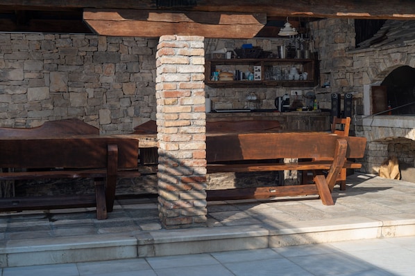 A rustic stone wall with a wooden bench and a stone fireplace.