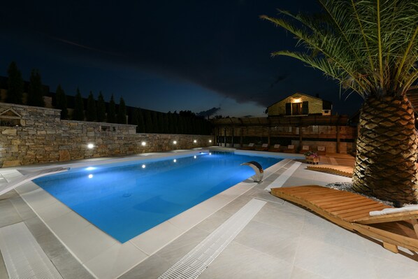 A swimming pool with a stone wall and a wooden deck.
