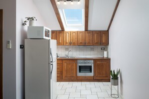 A kitchen with wooden cabinets, a white refrigerator, a built-in oven, and a skylight.