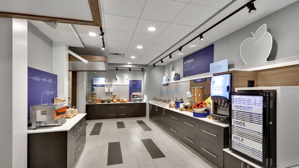 A modern kitchen with a central island, built-in appliances, and a digital menu display. - Holiday Inn Express Suites Plano East Richardson (Celina)